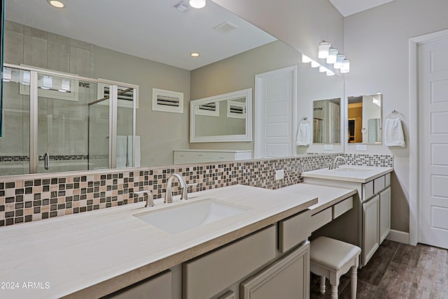 bathroom with decorative backsplash, a shower with shower door, wood-type flooring, and vanity