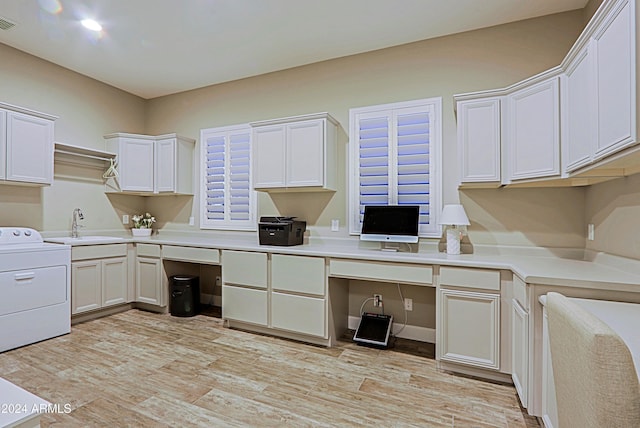 kitchen featuring washer / clothes dryer, sink, white cabinets, and built in desk