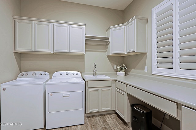 laundry area with washing machine and clothes dryer, sink, cabinets, and light wood-type flooring