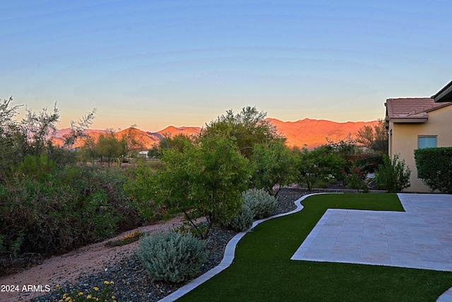 yard at dusk with a mountain view and a patio area