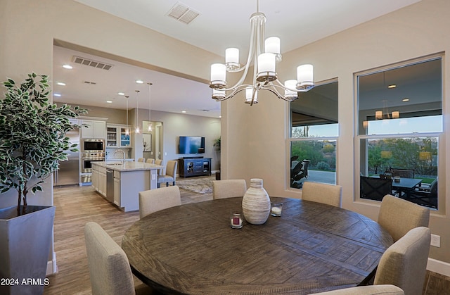 dining space featuring light hardwood / wood-style flooring, an inviting chandelier, and sink