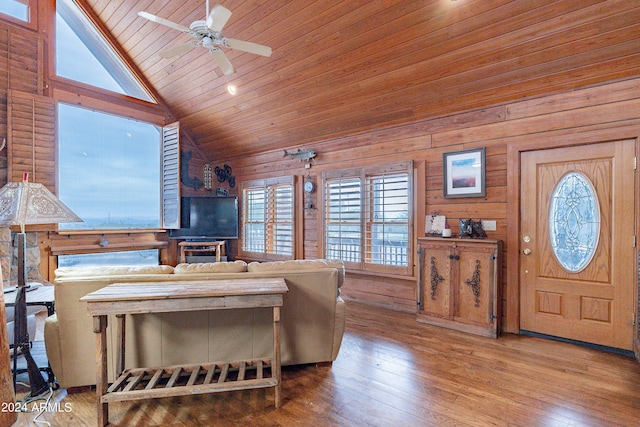 living room with wooden ceiling, wooden walls, vaulted ceiling, ceiling fan, and light hardwood / wood-style floors