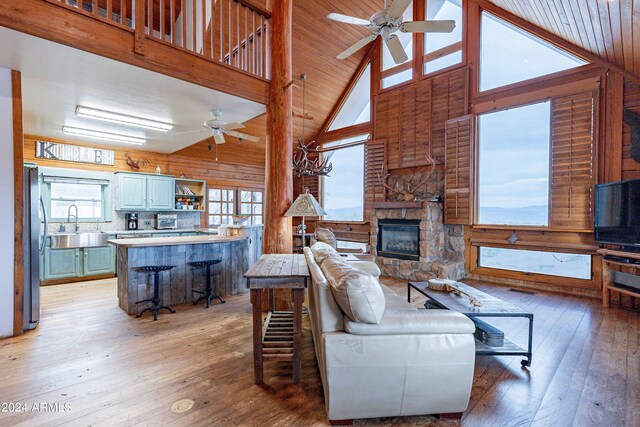 living room with a fireplace, hardwood / wood-style flooring, high vaulted ceiling, and wooden walls