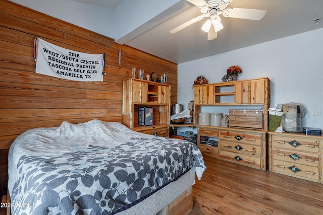 bedroom featuring ceiling fan, wood walls, and wood-type flooring