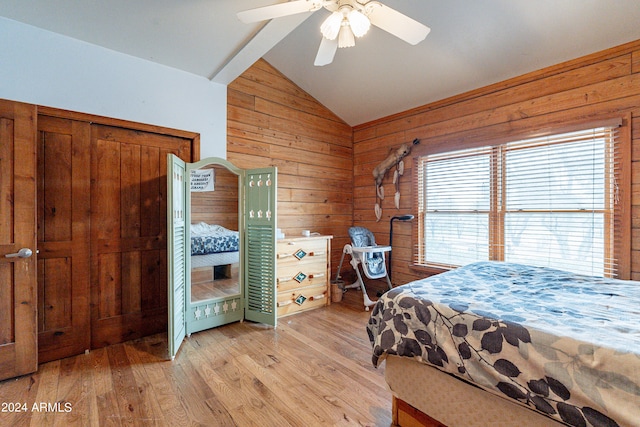 bedroom with ceiling fan, wooden walls, vaulted ceiling with beams, light hardwood / wood-style floors, and a closet