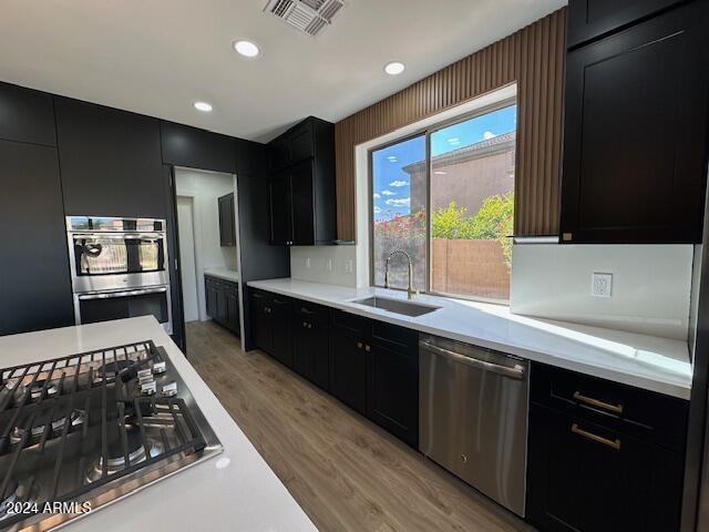 kitchen with stainless steel appliances, light hardwood / wood-style floors, and sink