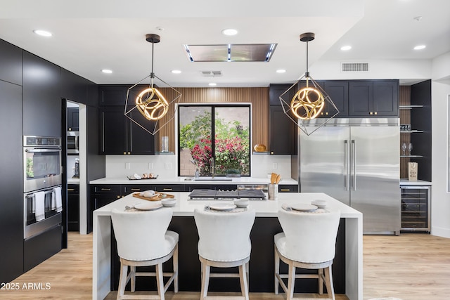 10646 E Butherus Dr, Scottsdale, AZ 85255 - kitchen with appliances with stainless steel finishes, beverage cooler, light countertops, a sink, and a chandelier