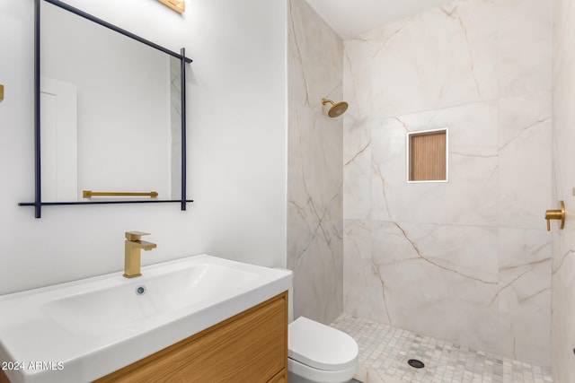 bathroom with tiled shower, vanity, and toilet