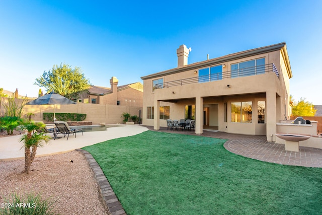 back of house featuring a yard, a patio area, and a balcony