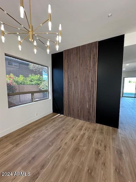 unfurnished room featuring a notable chandelier and wood-type flooring