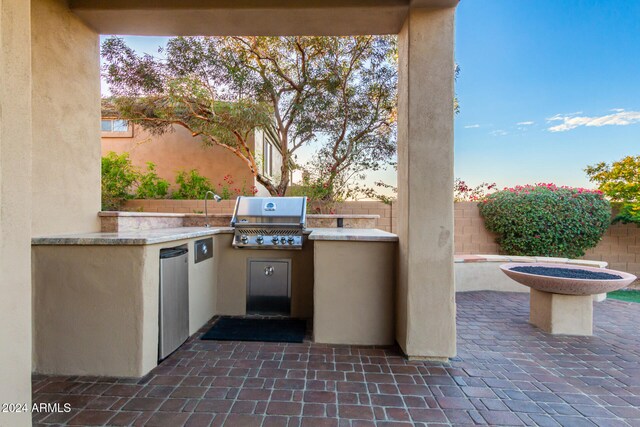 patio terrace at dusk featuring a grill and exterior kitchen