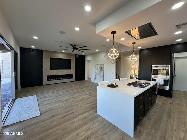 10646 E Butherus Dr, Scottsdale, AZ 85255 - kitchen featuring appliances with stainless steel finishes, dark cabinets, a center island, light wood finished floors, and recessed lighting