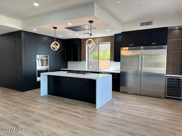 kitchen featuring a kitchen island, beverage cooler, pendant lighting, and appliances with stainless steel finishes