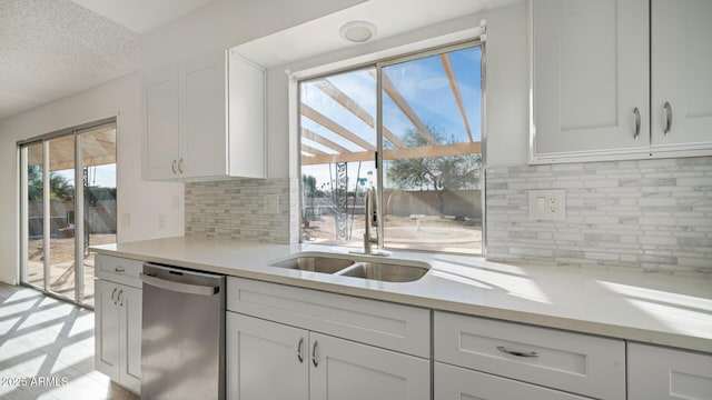 kitchen featuring tasteful backsplash, white cabinetry, sink, and stainless steel dishwasher