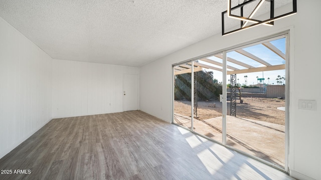 unfurnished room with wood-type flooring, a textured ceiling, and wood walls