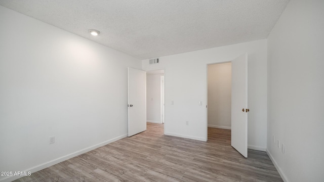 unfurnished room with light hardwood / wood-style floors and a textured ceiling