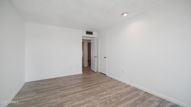 empty room with a textured ceiling and light wood-type flooring