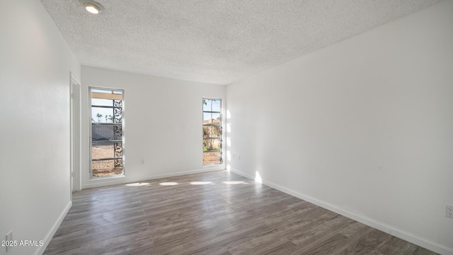 unfurnished room featuring dark wood-type flooring and a textured ceiling