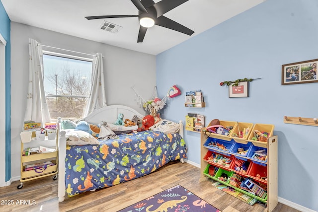 bedroom with a ceiling fan, visible vents, baseboards, and wood finished floors