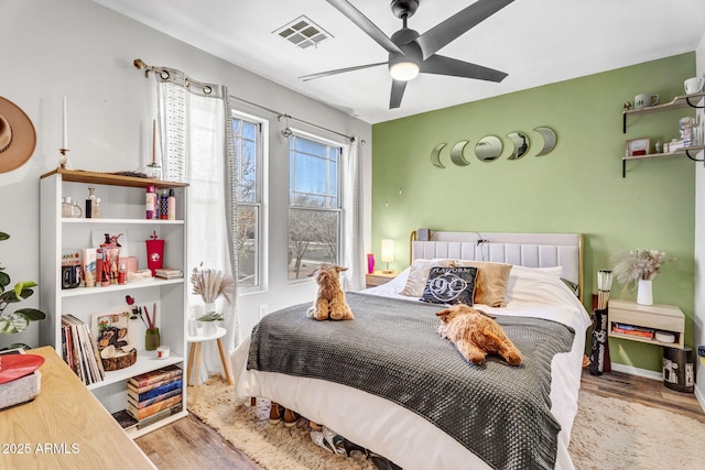 bedroom featuring ceiling fan, visible vents, and wood finished floors