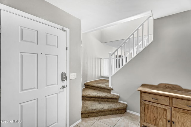 foyer entrance featuring stairway, light tile patterned flooring, and baseboards