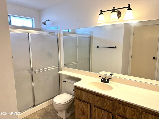 bathroom featuring tile patterned floors, vanity, toilet, and a shower with shower door