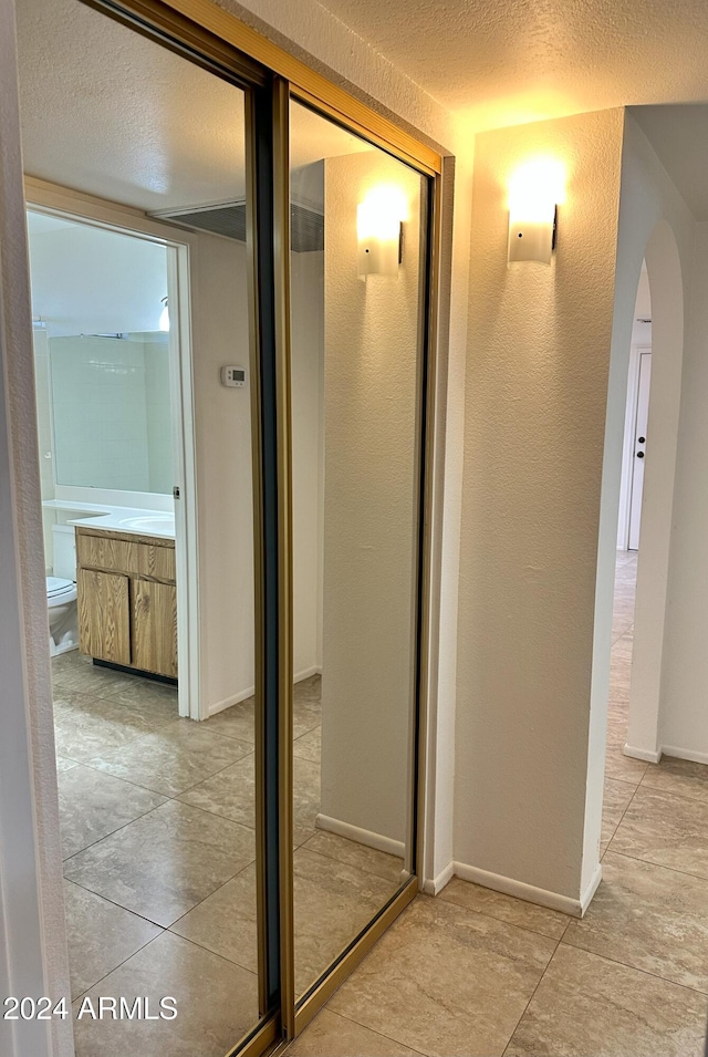 corridor with light tile patterned floors and a textured ceiling