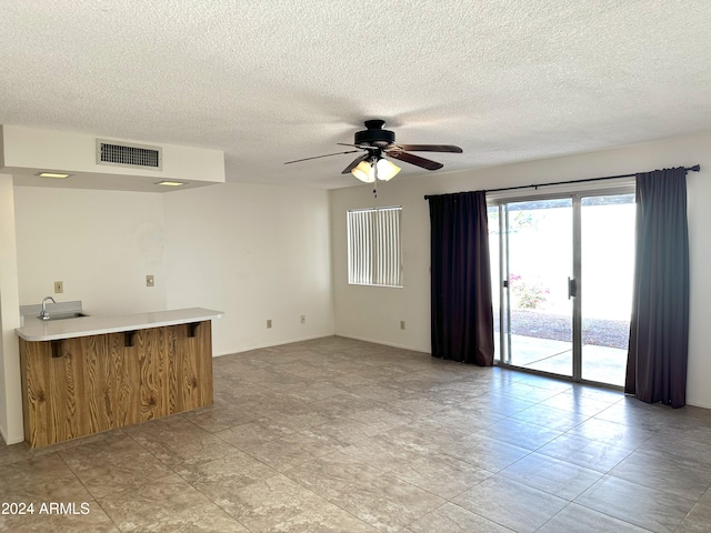 tiled spare room featuring a textured ceiling, ceiling fan, and sink