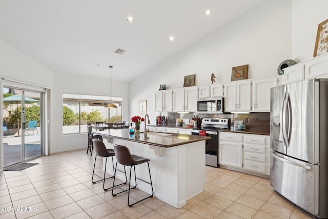 4936 E Villa Rita Dr, Scottsdale, AZ 85254 - kitchen with appliances with stainless steel finishes, dark countertops, white cabinetry, and a kitchen bar