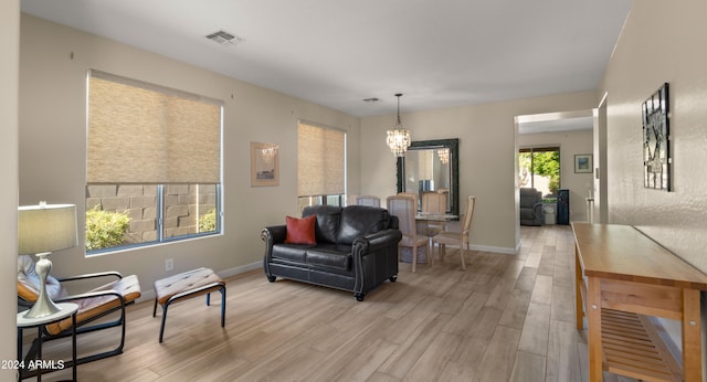 living room with a healthy amount of sunlight, a chandelier, and light wood-type flooring