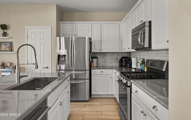 kitchen featuring appliances with stainless steel finishes, light hardwood / wood-style flooring, and white cabinets