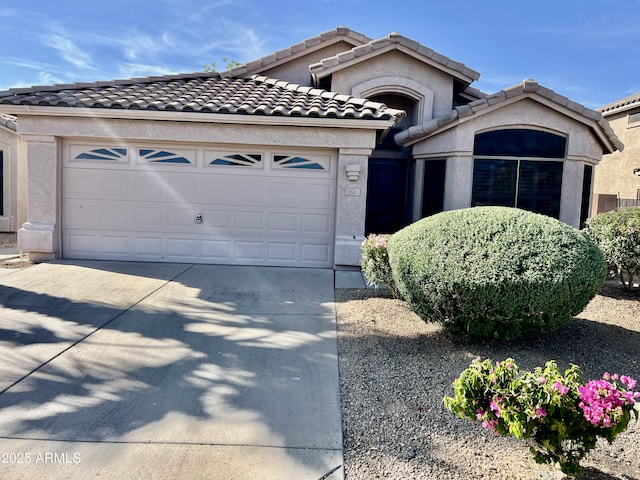 mediterranean / spanish house featuring an attached garage, stucco siding, driveway, and a tiled roof