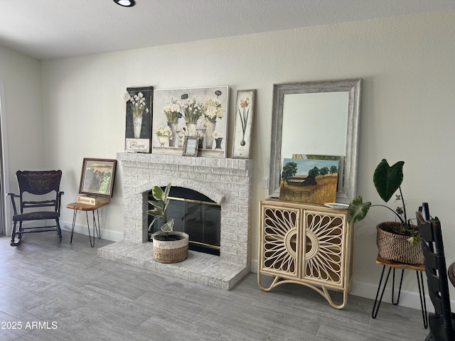 living area with baseboards and a brick fireplace