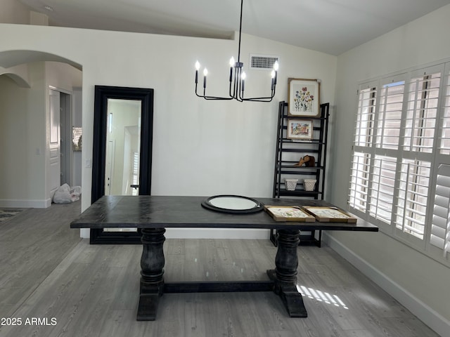 dining area featuring visible vents, lofted ceiling, wood finished floors, baseboards, and arched walkways