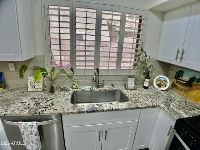 kitchen with white cabinetry, decorative backsplash, a sink, and dishwasher