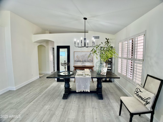 dining area featuring visible vents, an inviting chandelier, wood finished floors, arched walkways, and vaulted ceiling