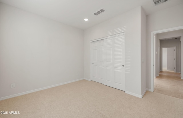 unfurnished bedroom featuring light carpet and a closet