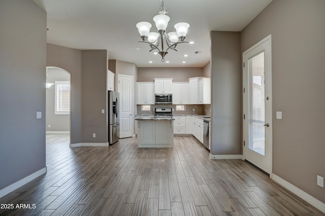 5552 N Kerwood Loop, Prescott Valley, AZ 86314 - kitchen with stainless steel appliances, arched walkways, wood finished floors, and a kitchen island