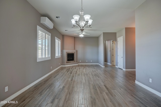5552 N Kerwood Loop, Prescott Valley, AZ 86314 - unfurnished living room with a wall mounted air conditioner, light wood-style floors, arched walkways, a chandelier, and a fireplace