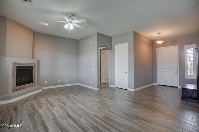 5552 N Kerwood Loop, Prescott Valley, AZ 86314 - unfurnished living room with a ceiling fan, wood finished floors, arched walkways, and a high end fireplace