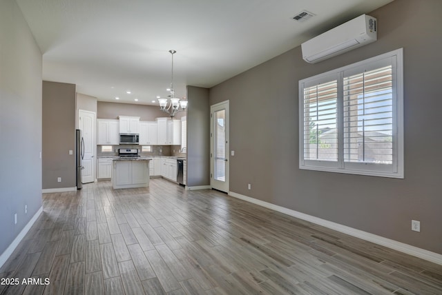 5552 N Kerwood Loop, Prescott Valley, AZ 86314 - kitchen featuring appliances with stainless steel finishes, a wall mounted air conditioner, open floor plan, a chandelier, and wood finished floors