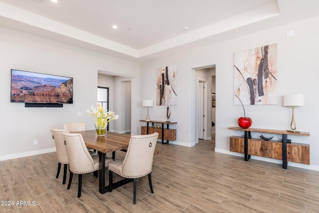 dining room featuring light wood-type flooring and a raised ceiling