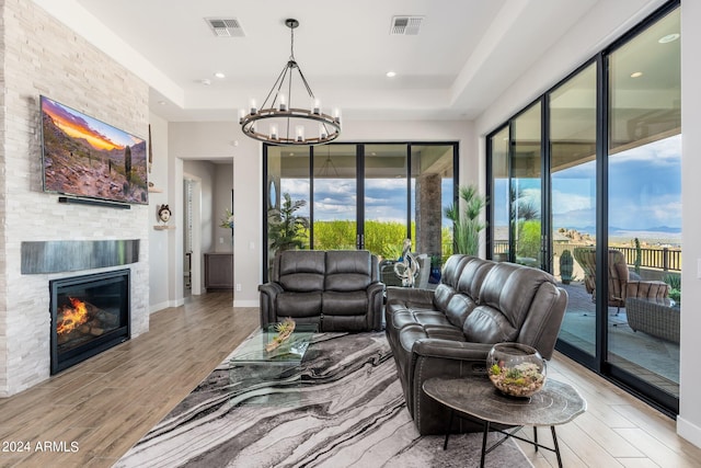 living room featuring a fireplace, plenty of natural light, light hardwood / wood-style floors, and a notable chandelier