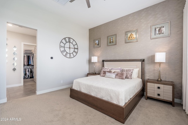 bedroom featuring light carpet, a spacious closet, ceiling fan, and a closet