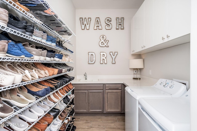 laundry room featuring cabinets, washer and clothes dryer, sink, and hardwood / wood-style floors