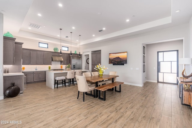 dining area with a tray ceiling and light hardwood / wood-style flooring