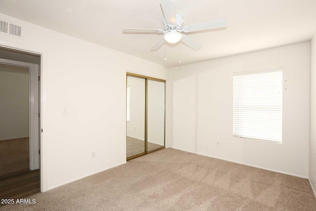 unfurnished bedroom with carpet, a closet, ceiling fan, and multiple windows