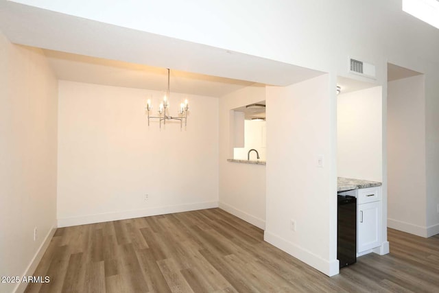 unfurnished dining area with wood finished floors, a chandelier, and baseboards