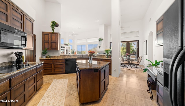 kitchen with dark stone countertops, ceiling fan, black appliances, and a center island