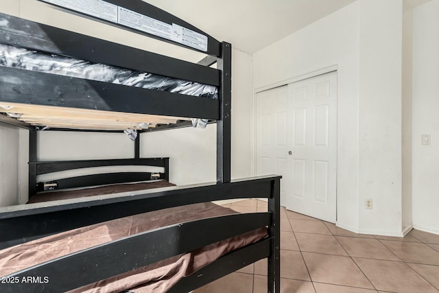 tiled bedroom featuring baseboards and a closet